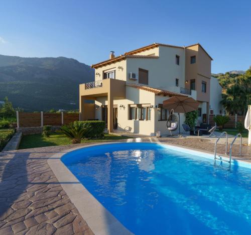 a villa with a swimming pool in front of a house at Family Villa Ellis Plakias with private pool 200m to the beach walking distance to the amenities in Plakias