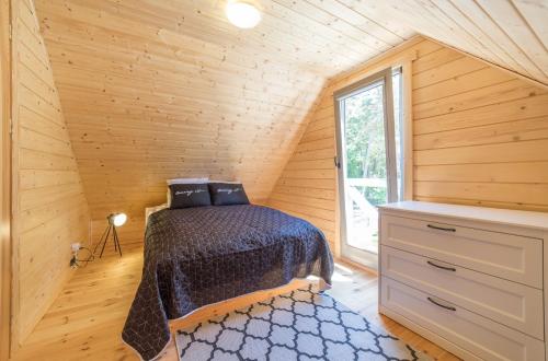 a bedroom with a bed in a room with a window at Domki Między Sosnami in Pobierowo