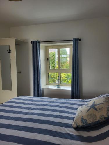a bedroom with a blue striped bed with a window at McGrath's Bar & Accommodation Causeway in Causeway