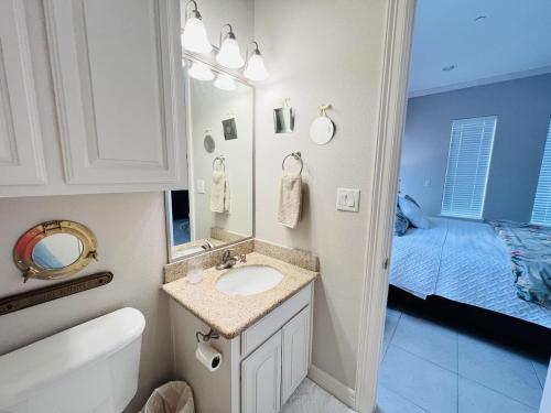 a bathroom with a sink and a mirror and a bed at Family Retreat with pool for 6 Pet Lovers 130 E Retama #3 in South Padre Island