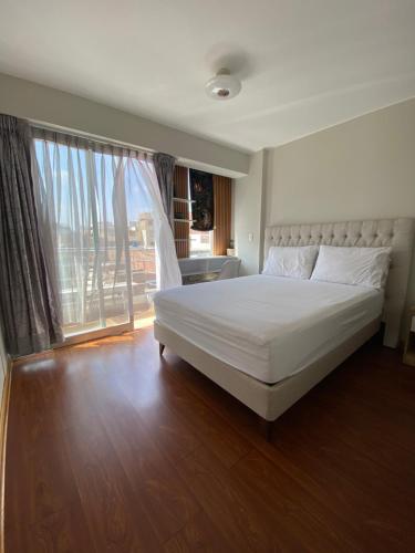 a bedroom with a white bed and a large window at Sai in Lima