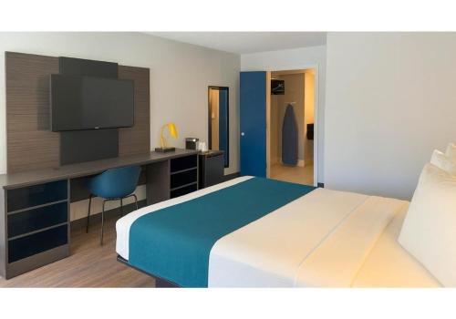 a bedroom with a bed and a desk with a television at Motel 6-Anaheim, CA - Maingate in Anaheim