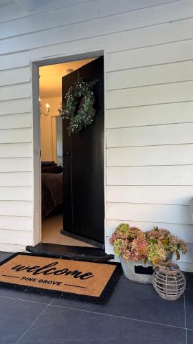 a door to a house with two potted plants on the porch at Pinegrove Cottage - Greytown Getaway in Woodside