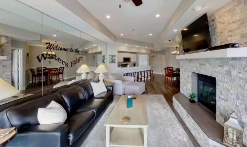 a living room with a black leather couch and a fireplace at Waters Edge in Lake Ozark