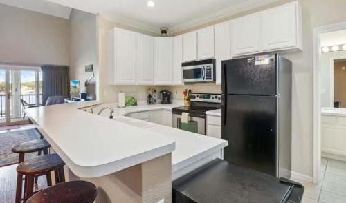 a kitchen with white cabinets and a black refrigerator at Lakeside Lookout in Sunrise Beach