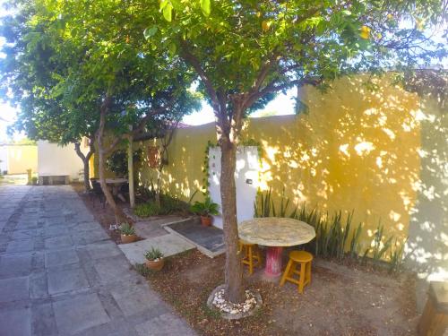 a table next to a tree next to a wall at Canto da Onda - Trilha exclusiva para a praia in Marechal Deodoro