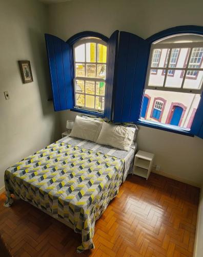 a bed in a room with two windows at Casa Carmo in Ouro Preto
