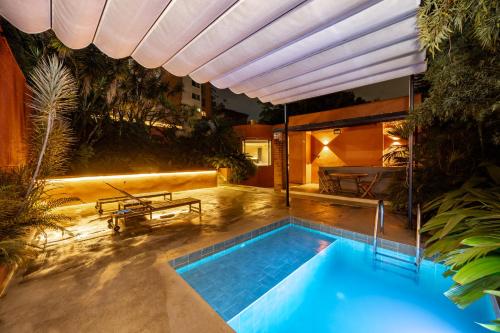 a swimming pool in a backyard with a large umbrella at Casa Penta Top Notch Villa in Medellín