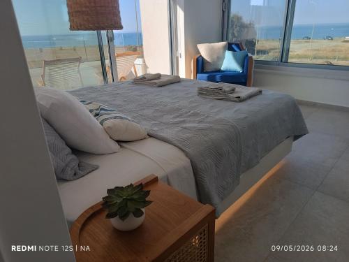 a bedroom with a bed with a table and a chair at Blue Aura Beach villa Larnaca in Perivolia