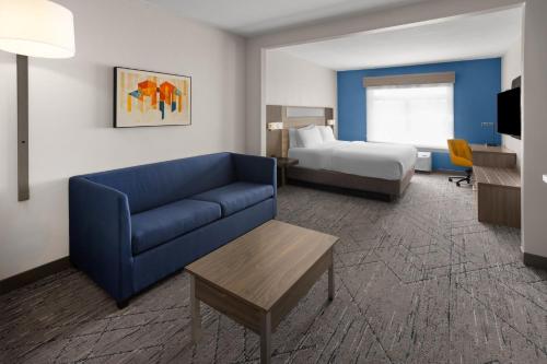 a hotel room with a couch and a bed at Holiday Inn Express Syracuse-Fairgrounds by IHG in Warners