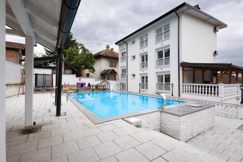 a swimming pool in front of a white building at Lumina Residence in Sarajevo