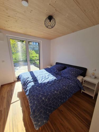 a bedroom with a bed with a blue comforter and a window at 5lakes & nature in Starnberg