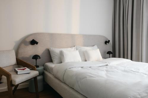 a bedroom with a large white bed and a chair at Nowy Sącz Apartamenty in Nowy Sącz