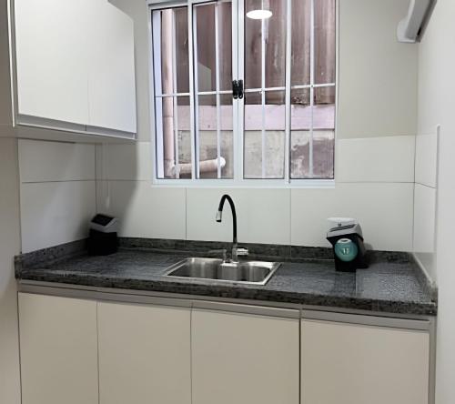 a kitchen counter with a sink and a window at Madonna Prime Studio Hotel Extrema MG + breakfast in Extrema