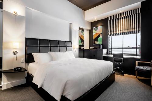 a bedroom with a large white bed and a desk at Hôtel Alt Québec in Quebec City