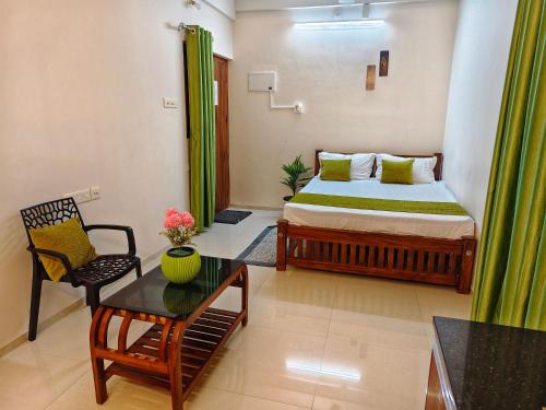 a bedroom with a bed and a chair and a table at Krishna Theeram 150m from Temple in Guruvāyūr