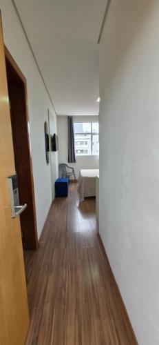 a hallway with a room with a bed and wooden floors at Paris Flats Lagoa Santa in Lagoa Santa