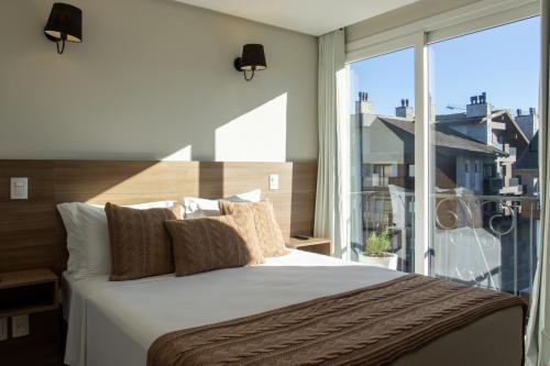a bedroom with a large bed and a large window at Augusta Centro Hotel in Canela