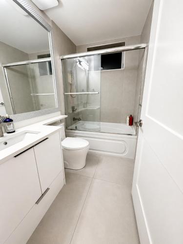 a white bathroom with a toilet and a shower at Modern Vancouver 2BR Suite Full Kitchen & Laundry in Vancouver