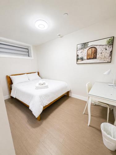 a white bedroom with a bed and a desk at Modern Vancouver 2BR Suite Full Kitchen & Laundry in Vancouver