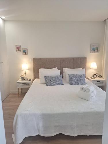 a bedroom with a large white bed with blue pillows at Vista Mar in Amorosa