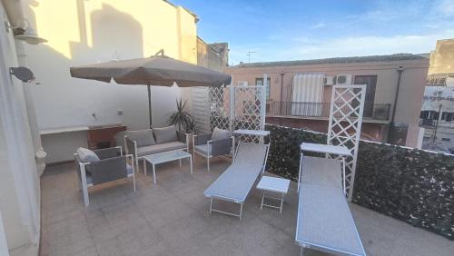 a patio with chairs and an umbrella on a balcony at Archimede29 in Syracuse