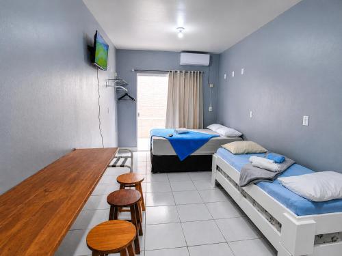 a room with two beds and a table and chairs at Recanto dos Pássaros 306C Até 10x Sem Juros no Cartão Direto com a Propriedade in Itapema