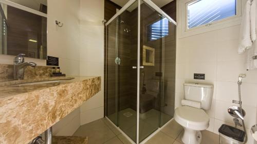a bathroom with a toilet and a glass shower at Augusta Centro Hotel in Canela