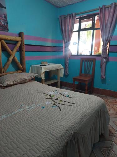 a bedroom with a bed with blue walls and a window at Hotel Casa Ramos in Panajachel