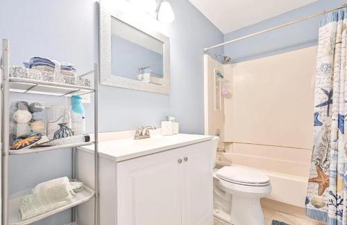 a white bathroom with a toilet and a sink at Beach Block Ocean Views steps from the boardwalk in Ocean City