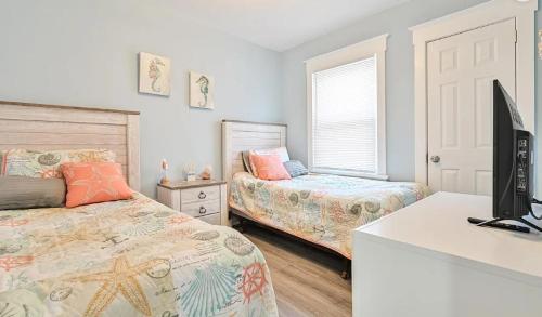 a bedroom with two beds and a desk with a television at Beach Block Ocean Views steps from the boardwalk in Ocean City