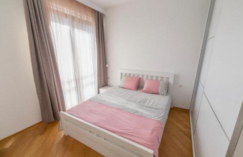a small bedroom with a bed with pink pillows at Boreti Apartment in Budva