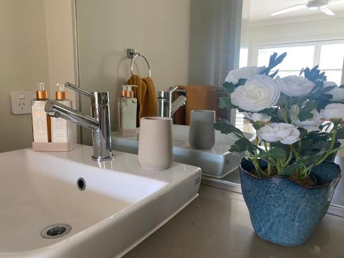 a bathroom sink with a vase of flowers on it at Huntlee Getaway in Branxton