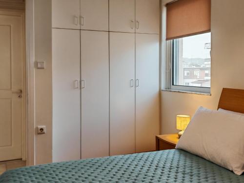 a bedroom with white cabinets and a bed with a window at Elenas sweet home - Penthouse with Large Balcony in Pyrgos