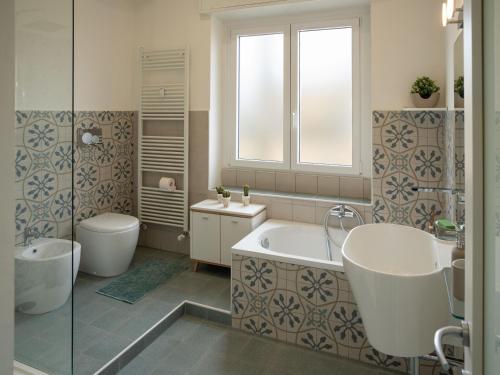 a bathroom with a tub and a toilet and a sink at Testa tra le Nuvole - Attico con Terrazza panoramica in centro in Novi Ligure