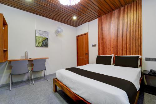 a bedroom with a large bed and a desk and a table at Super Hotel O AM Grandd in Kāraikkudi