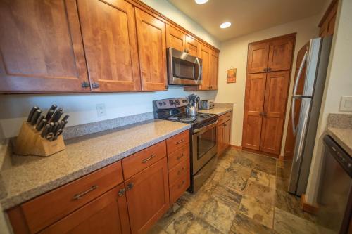 a kitchen with wooden cabinets and a stove top oven at Pines 2147 by SummitCove Lodging in Colorado in Keystone