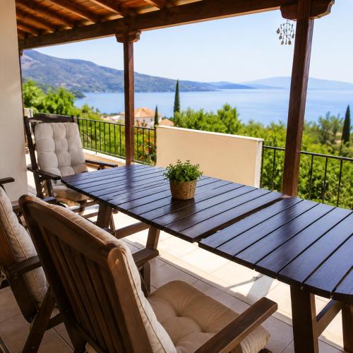 a wooden table on a patio with a view of the ocean at Aegina Breeze House in Egina