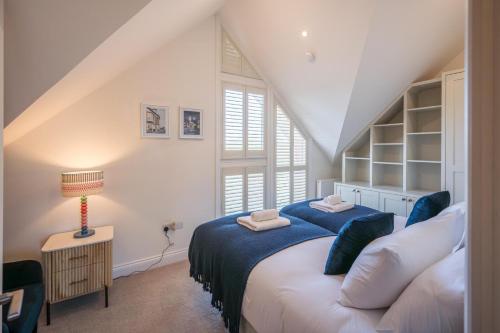 a bedroom with a bed with blue sheets and a window at Orange House, Southwold in Southwold