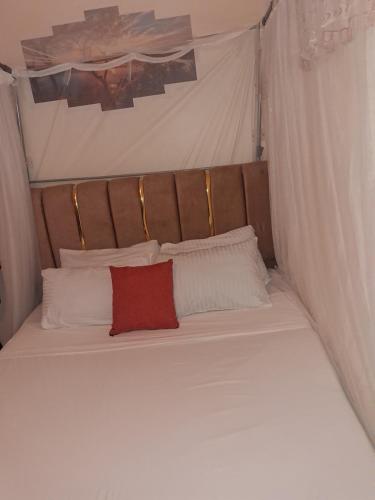 a large white bed with a red pillow on it at Town Stays in Voi