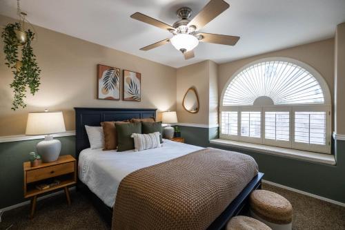 a bedroom with a bed with a ceiling fan and a window at Gilbert Beachcomber in Gilbert