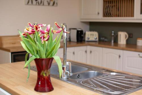 a vase filled with flowers sitting on a kitchen counter at 4 Bed in Fakenham oc-1261 in Thursford