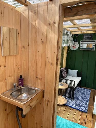 ein Badezimmer mit einem Waschbecken in einer Holzwand in der Unterkunft Forest Camping with grillhouse and dush in Lõupõllu