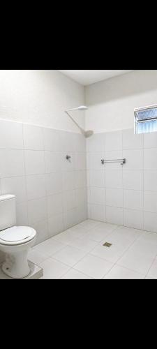a white bathroom with a toilet and a window at Pousada Bom Jesuss in Juazeiro do Norte