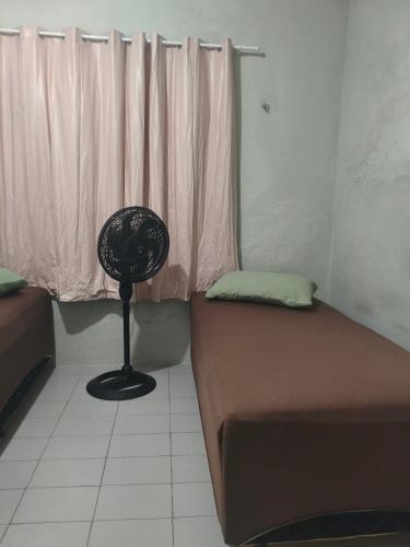 a room with a bed and a fan next to a window at Pousada Bom Jesuss in Juazeiro do Norte