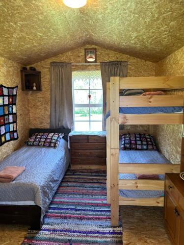 zwei Etagenbetten in einem Zimmer mit Fenster in der Unterkunft Forest Camping with grillhouse and dush in Lõupõllu