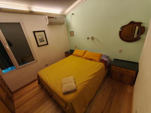a small bedroom with a bed with a yellow blanket at Alojamiento Tía Silvia in San José