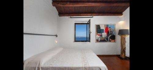 a white bedroom with a bed and a mirror at Seafront wow appartamento Baja Sardinia in Baja Sardinia