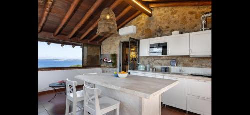 a kitchen with a large island with white cabinets at Seafront wow appartamento Baja Sardinia in Baja Sardinia