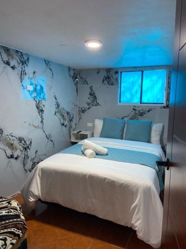 a bedroom with a large bed in a room with blue walls at Dalejadrohouse in Baños